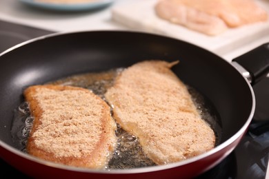 Photo of Cooking schnitzel in frying pan on stove, closeup