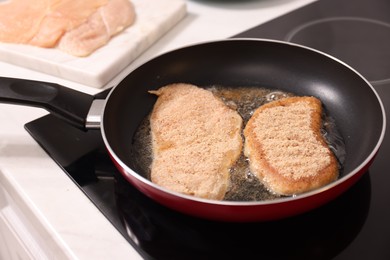 Photo of Cooking schnitzel in frying pan on stove, closeup