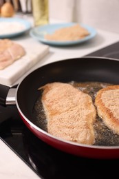 Photo of Schnitzels cooking in frying pan on stove, closeup