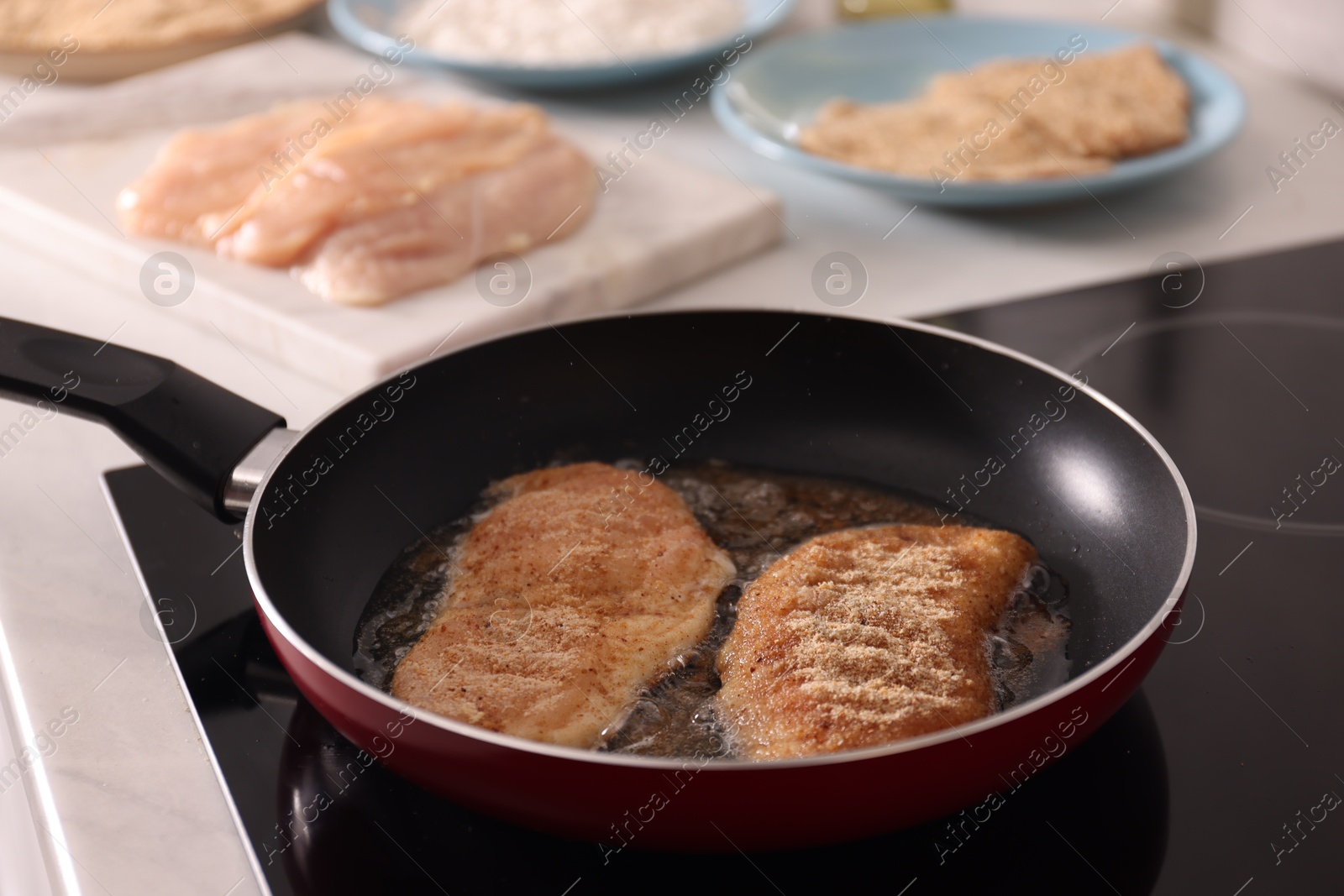 Photo of Schnitzels cooking in frying pan on stove, closeup