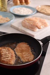 Photo of Schnitzels cooking in frying pan on stove, closeup