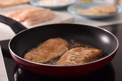 Photo of Schnitzels cooking in frying pan on stove, closeup