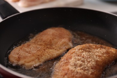 Photo of Schnitzels cooking in frying pan on stove, closeup