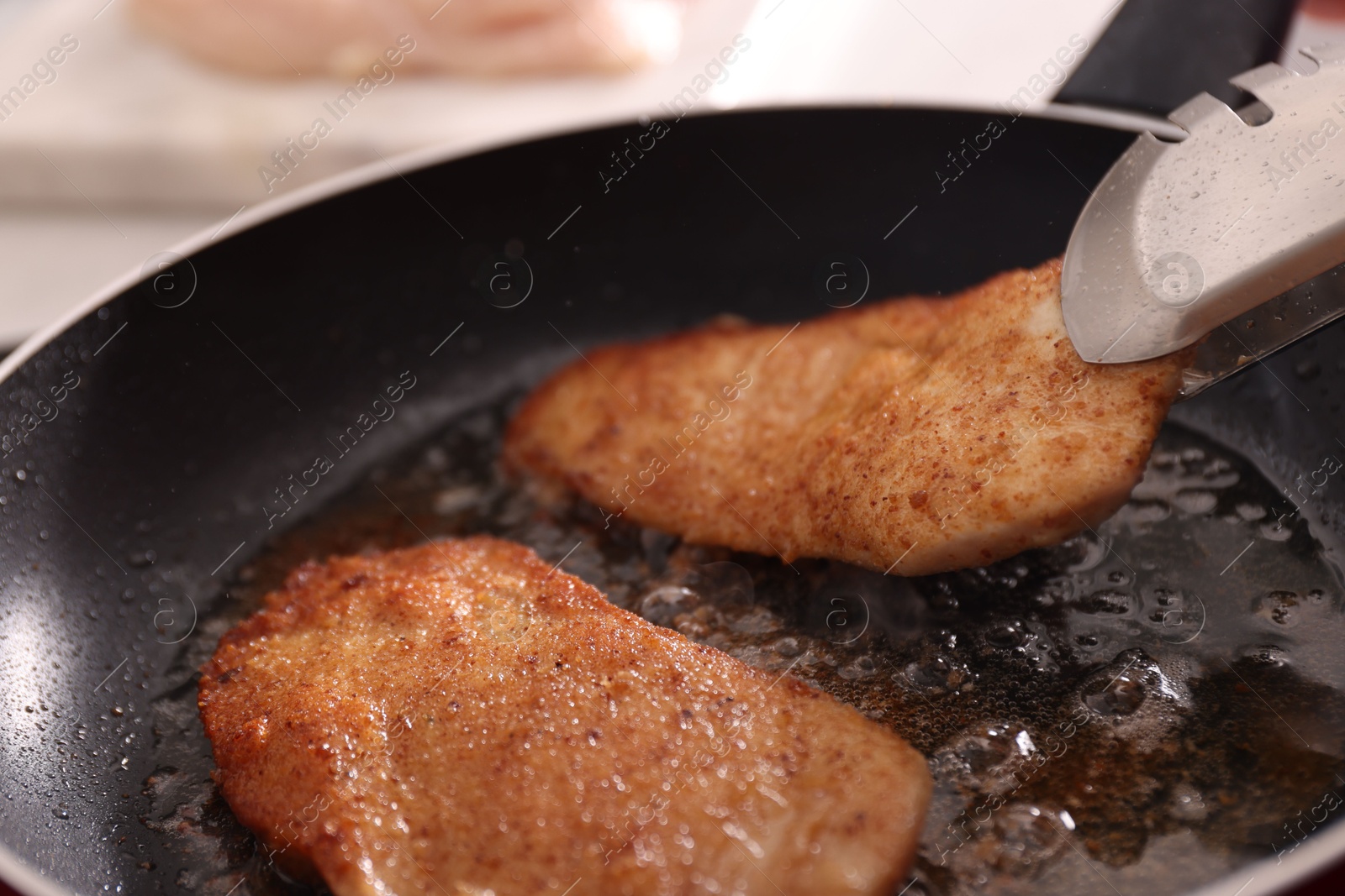 Photo of Schnitzels cooking in frying pan on stove, closeup