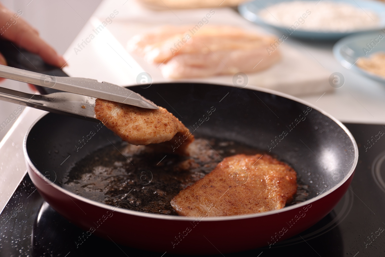 Photo of Woman cooking schnitzels in frying pan on stove, closeup