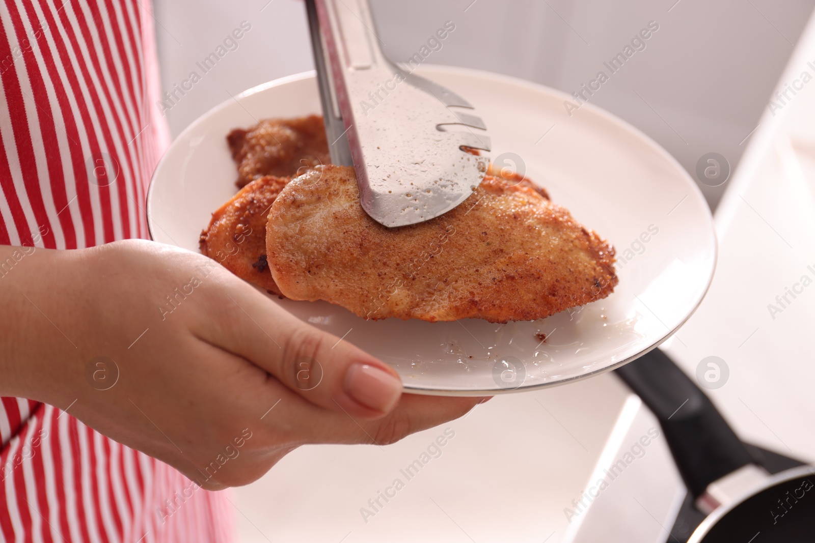 Photo of Woman cooking schnitzels in frying pan on stove, closeup