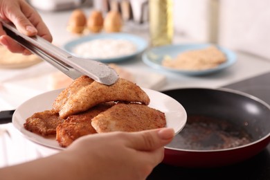 Woman cooking schnitzels in frying pan on stove, closeup