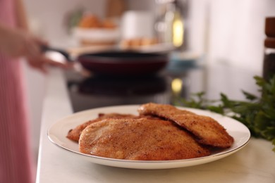 Plate of tasty schnitzels on table in kitchen, closeup