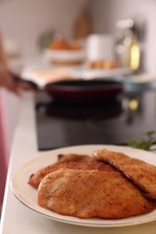 Plate of tasty schnitzels on table in kitchen, closeup