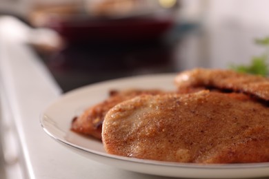 Photo of Plate of tasty schnitzels on table in kitchen, closeup