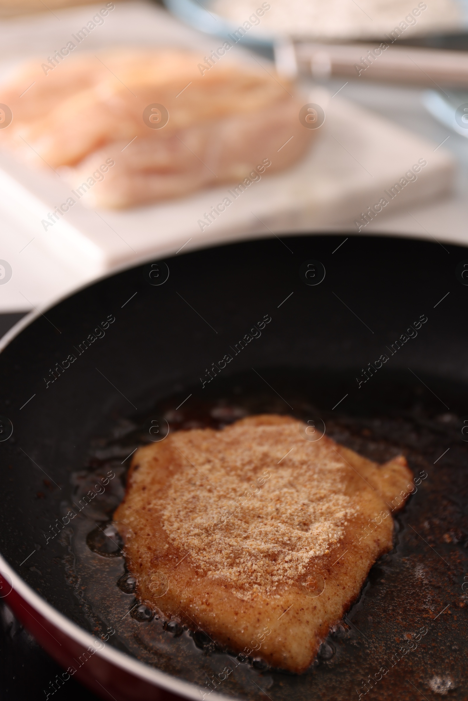 Photo of Cooking schnitzel in frying pan on stove, closeup