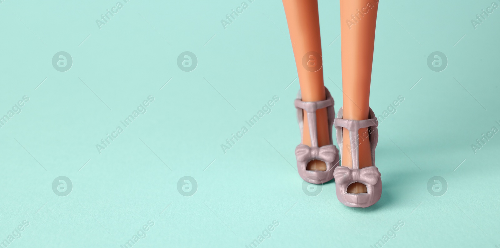 Image of Doll's legs with fancy shoes on turquoise background, banner design. Space for text