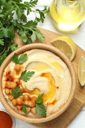 Photo of Delicious hummus with olive oil, chickpeas and parsley served on white wooden table, flat lay