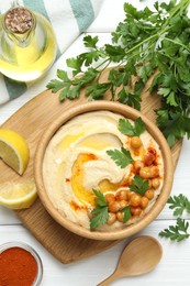 Delicious hummus with olive oil, chickpeas and parsley served on white wooden table, flat lay