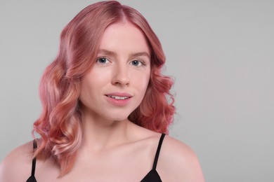 Image of Pretty young woman with pink hair on grey background, space for text