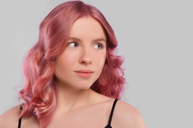 Image of Pretty young woman with pink hair on light grey background, space for text