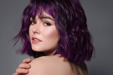 Image of Beautiful young woman with purple hair on grey background
