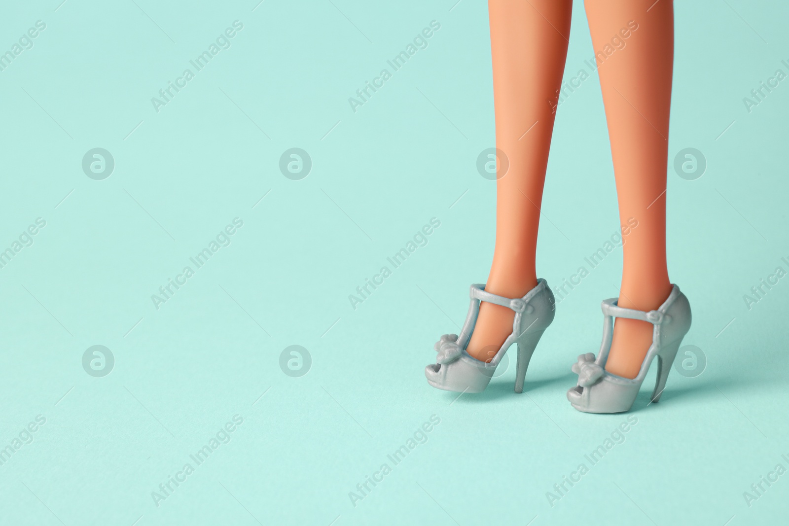 Image of Doll's legs with fancy shoes on turquoise background. Space for text