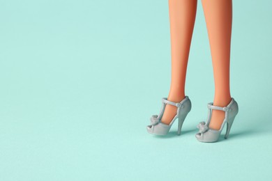 Image of Doll's legs with fancy shoes on turquoise background. Space for text