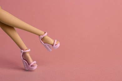 Image of Doll's legs with fancy shoes on coral background. Space for text