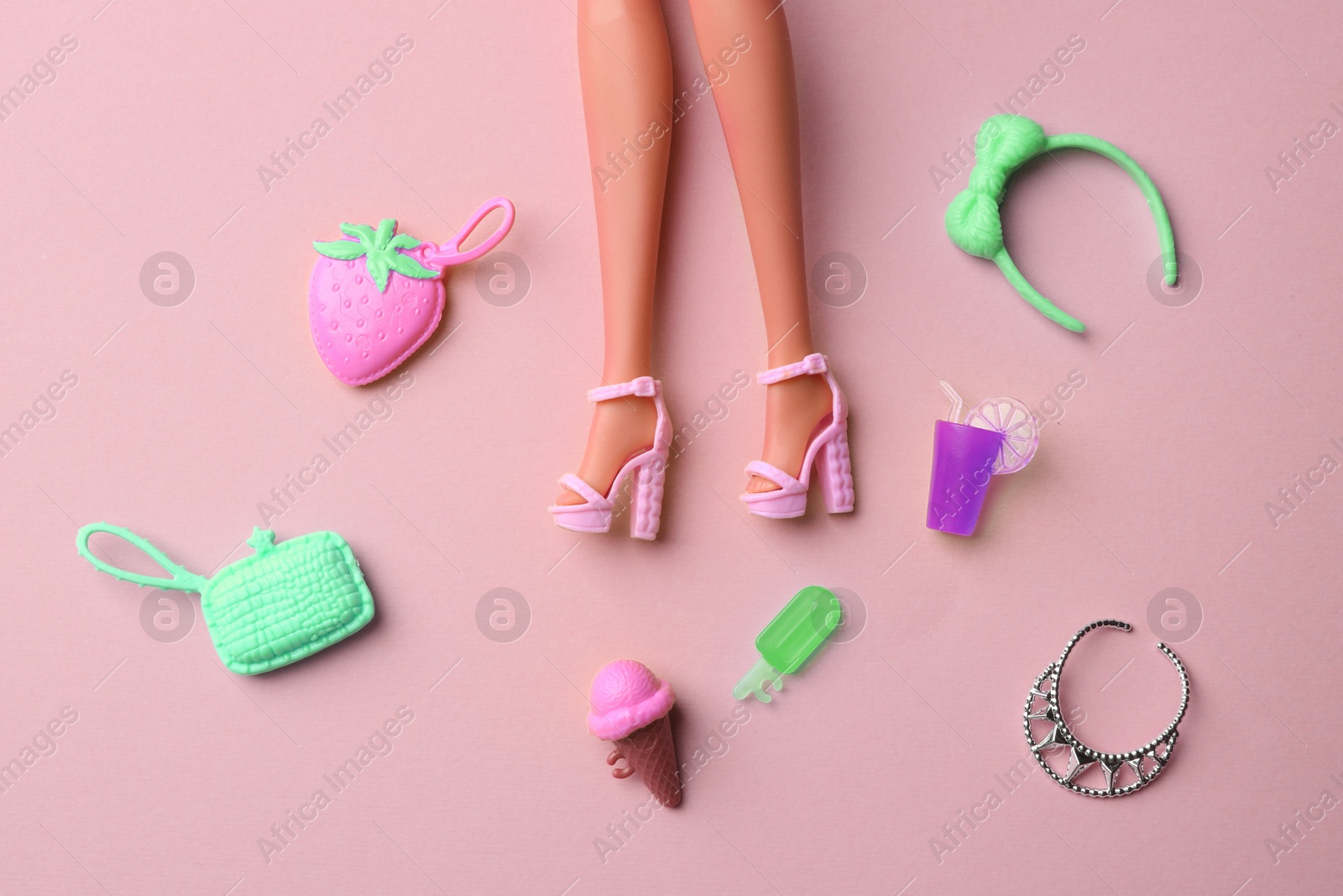 Image of Doll's legs with fancy shoes and different accessories on beige pink background