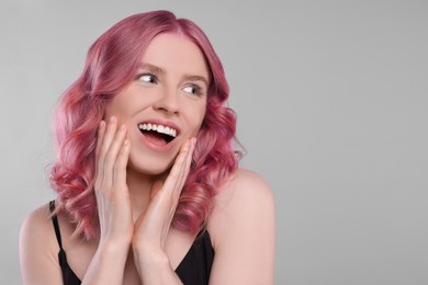 Image of Happy girl with pink hair on grey background, space for text