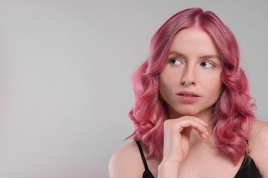 Image of Pretty young woman with pink hair on grey background, space for text