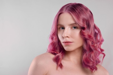 Image of Pretty young woman with pink hair on light grey background, space for text