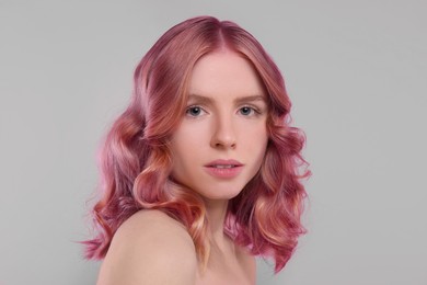 Image of Pretty young woman with pink hair on grey background
