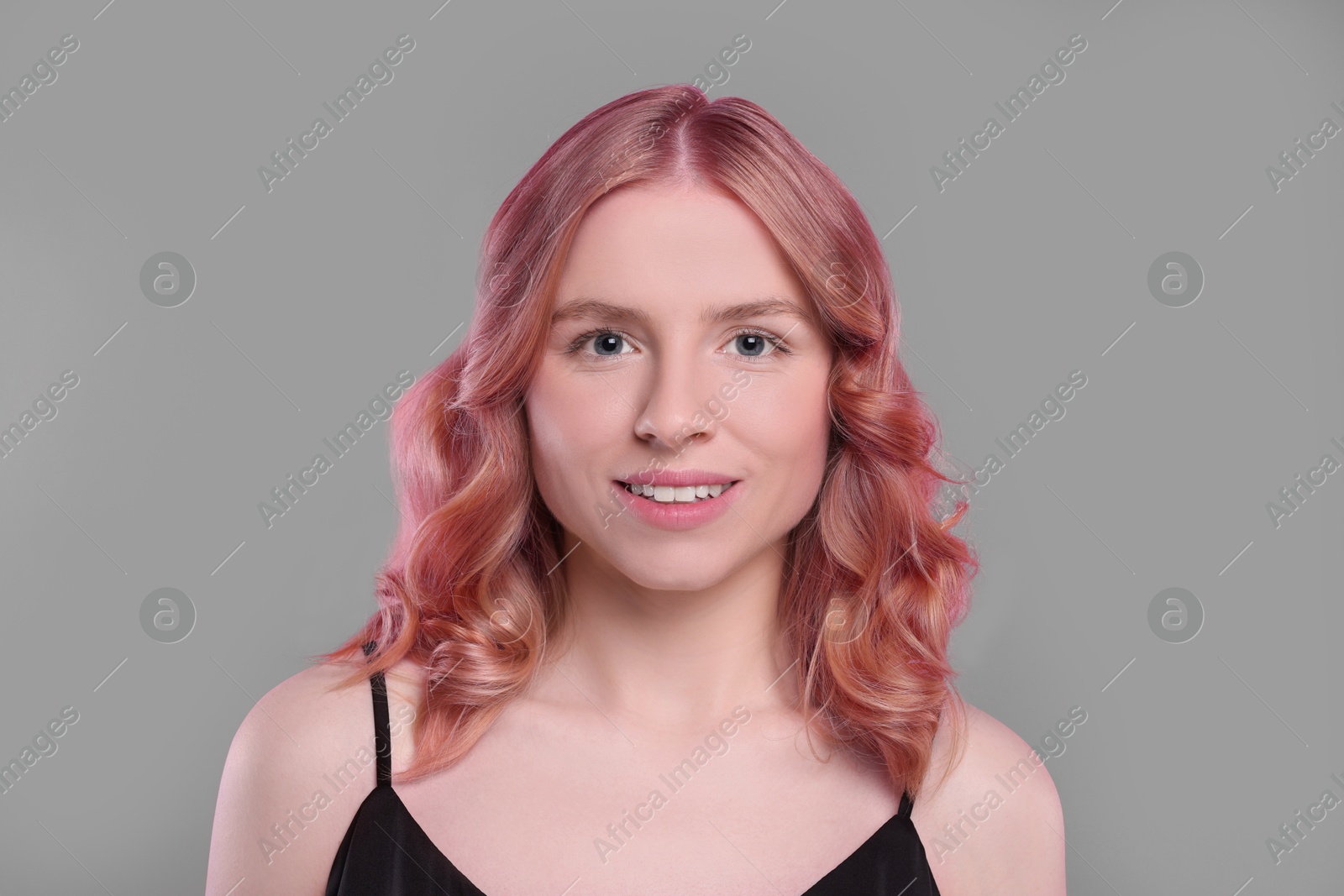 Image of Pretty young woman with pink hair on grey background