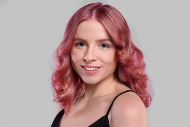 Pretty young woman with pink hair on light grey background