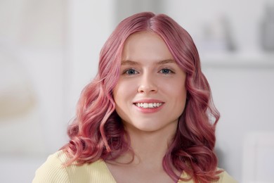 Pretty young woman with pink hair indoors