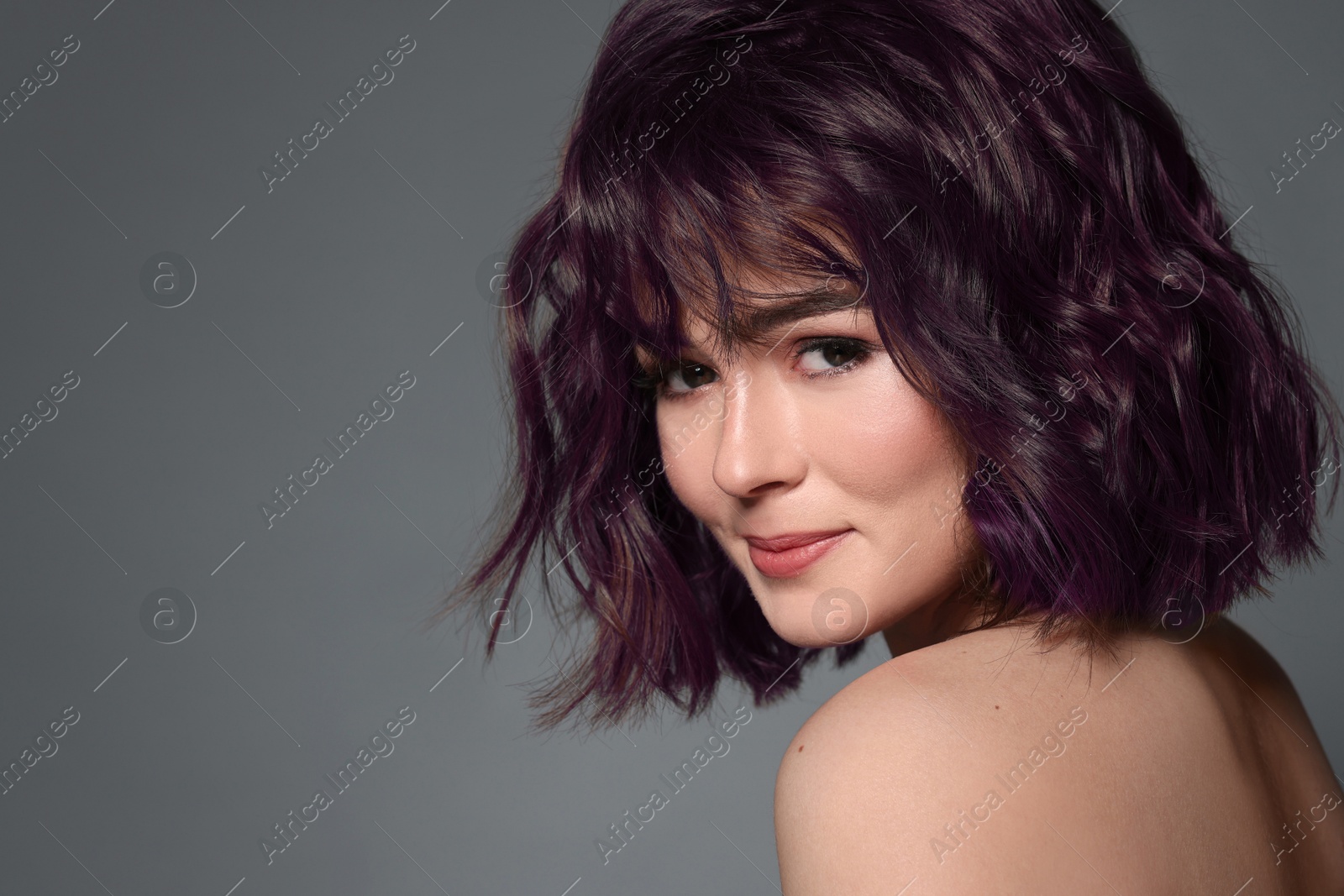 Image of Beautiful young woman with purple hair on grey background