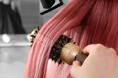 Image of Hairdresser blow drying client's pink hair in salon, closeup