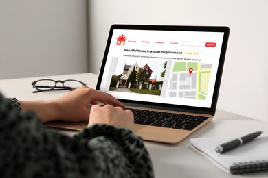 Woman choosing dwelling on house hunting website via laptop at table, closeup