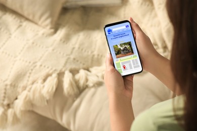 Image of Woman choosing dwelling on house hunting website via smartphone indoors, closeup