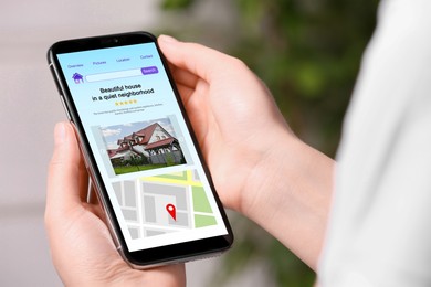 Woman choosing dwelling on house hunting website via smartphone, closeup