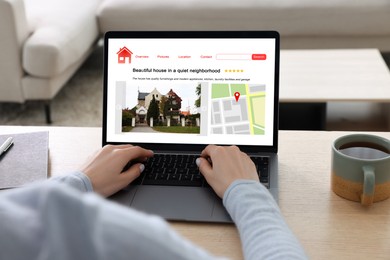 Image of Woman choosing dwelling on house hunting website via laptop at table, closeup