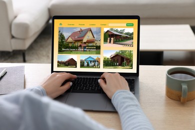 Image of Woman choosing dwelling on house hunting website via laptop at table, closeup