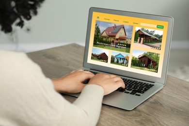 Image of Woman choosing dwelling on house hunting website via laptop at table, closeup