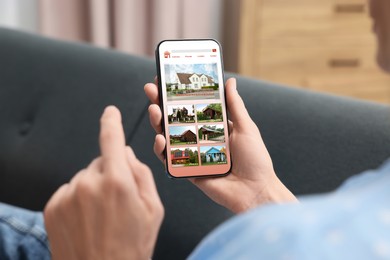 Woman choosing dwelling on house hunting website via smartphone indoors, closeup