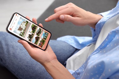 Woman choosing dwelling on house hunting website via smartphone indoors, closeup