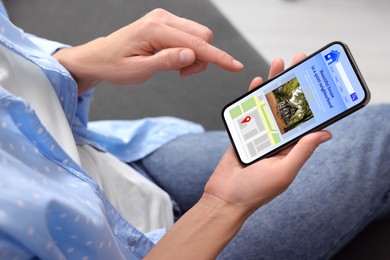 Image of Woman choosing dwelling on house hunting website via smartphone indoors, closeup