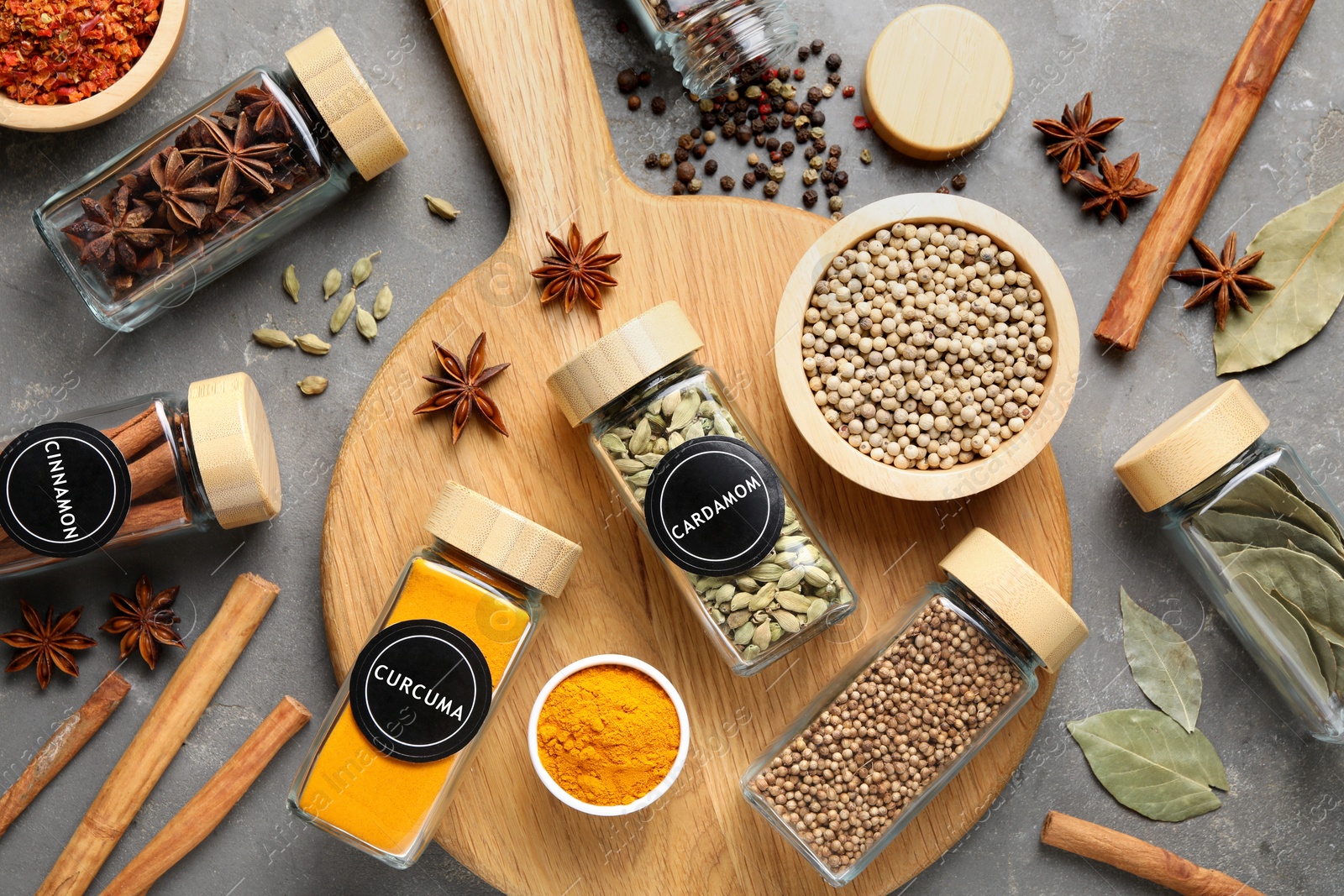 Image of Labelled jars with spices on grey table, flat lay