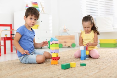 Photo of Cute little children playing with colorful blocks on floor indoors. Educational toy