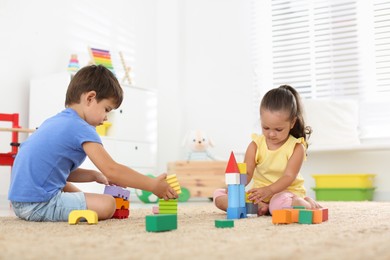 Photo of Cute little children playing with colorful blocks on floor indoors. Educational toy