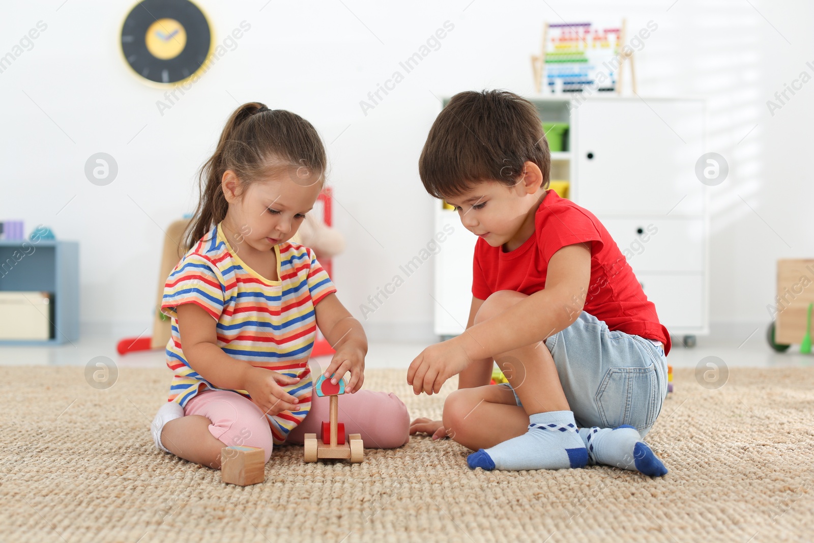 Photo of Cute little children playing with toys on floor at home