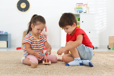 Cute little children playing with toys on floor at home