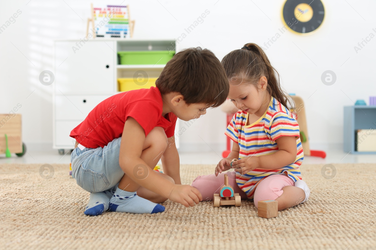 Photo of Cute little children playing with toys on floor at home