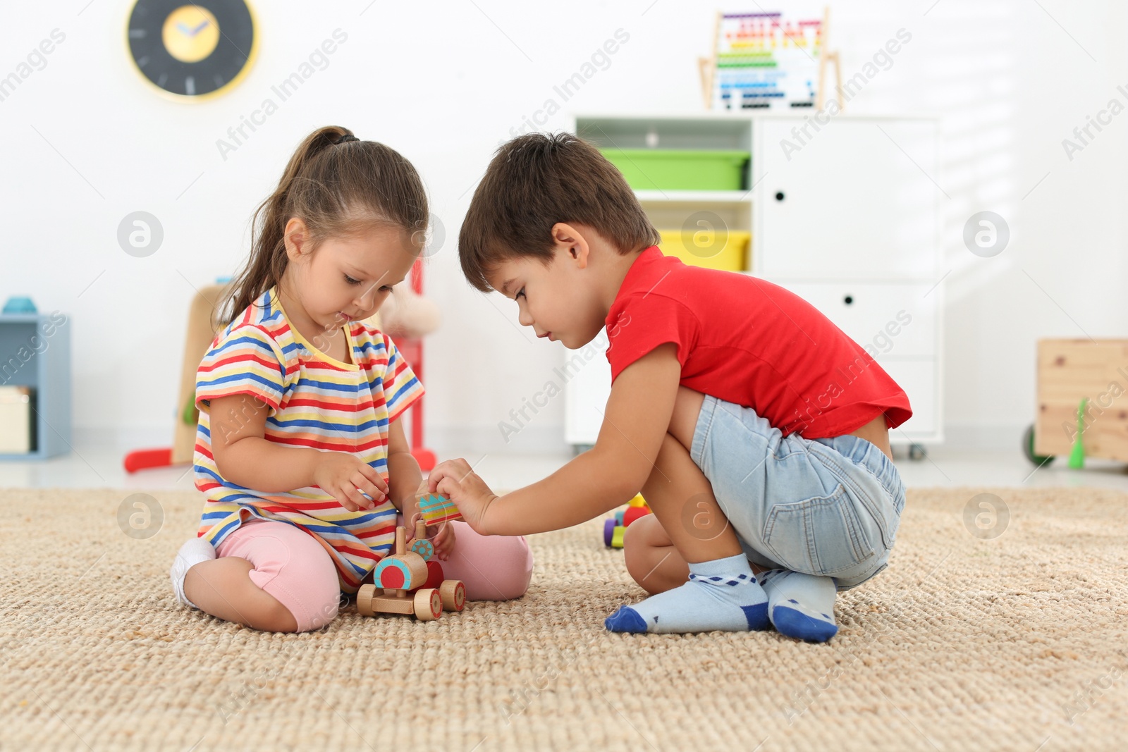 Photo of Cute little children playing with toys on floor at home